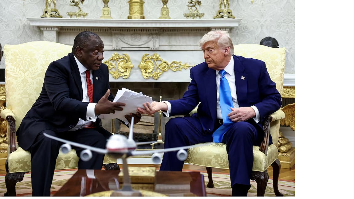 দক্ষিণ আফ্রিকার প্রেসিডেন্ট সিরিল রামাফোসার (বাঁয়ে) কাছে পত্রিকার কাটিং তুলে দিচ্ছেন যুক্তরাষ্ট্রের প্রেসিডেন্ট ডোনাল্ড ট্রাম্প। হোয়াইট হাউসের ওভাল অফিসে,  ২১ মে ২০২৫