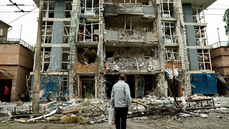 কিয়েভে রাশিয়ার হামলায় বিধ্বস্ত একটি ভবনের সামনে দাঁড়িয়ে আছেন স্থানীয় এক বাসিন্দা