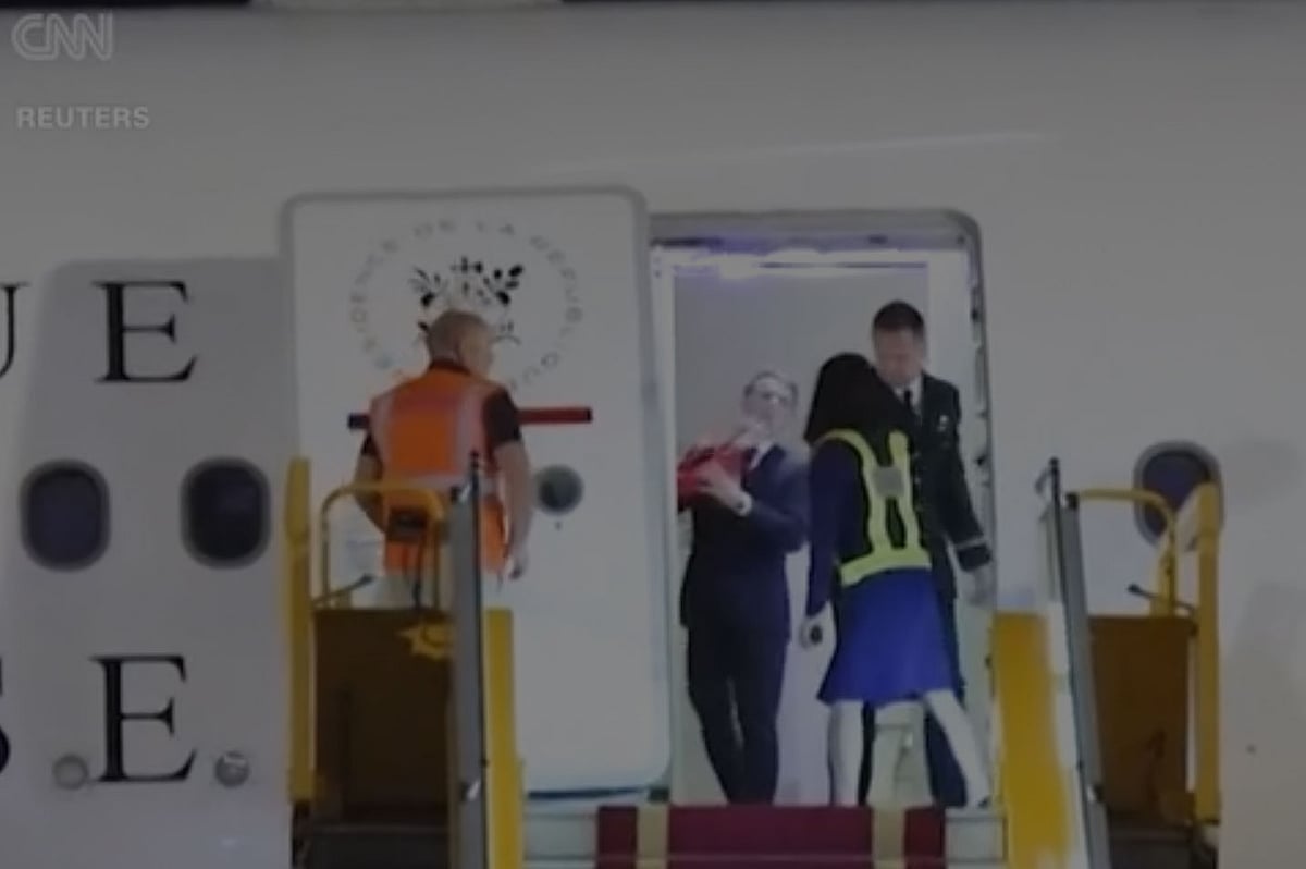 এমানুয়েল মাখোঁ ব্রিজিতের দুটি হাত পাশ থেকে হঠাৎ প্রেসিডেন্টের মুখে পড়তে দেখা যায়, যা অনেকটা চপেটাঘাত বলে মনে হয়েছে। হ্যানয়ের নই বাই আন্তর্জাতিক বিমানবন্দরে উড়োজাহাজে, ২৫ মে ২০২৫