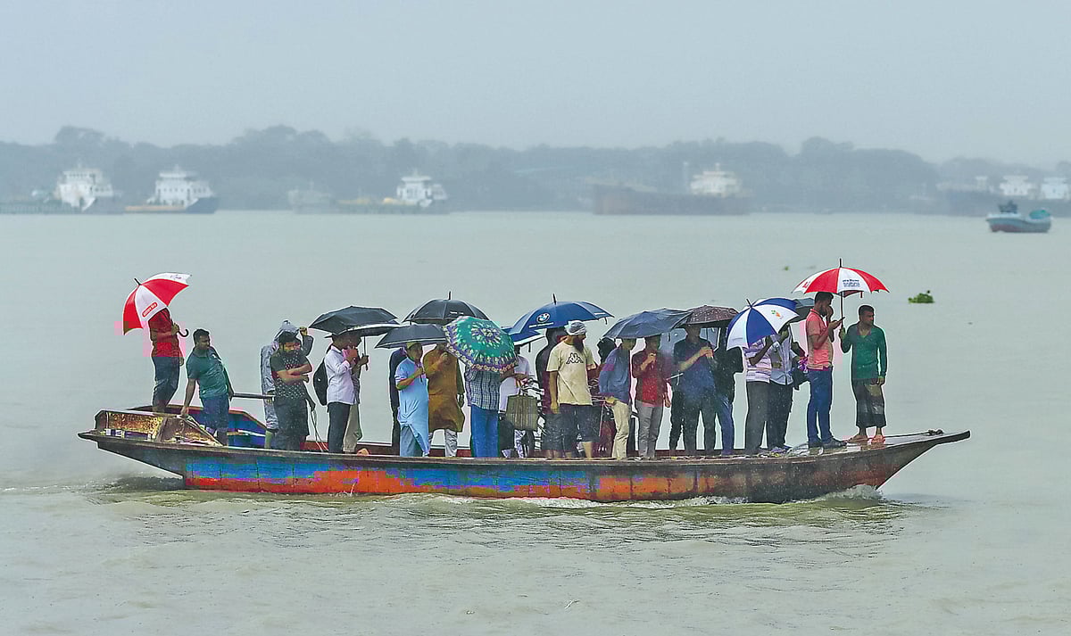 বৈরী আবহাওয়ার মধ্যে ছাতা মাথায় ট্রলারে কীর্তনখোলা নদী পার হচ্ছেন যাত্রীরা। গতকাল বেলা সোয়া তিনটায় বরিশাল নদীবন্দরে