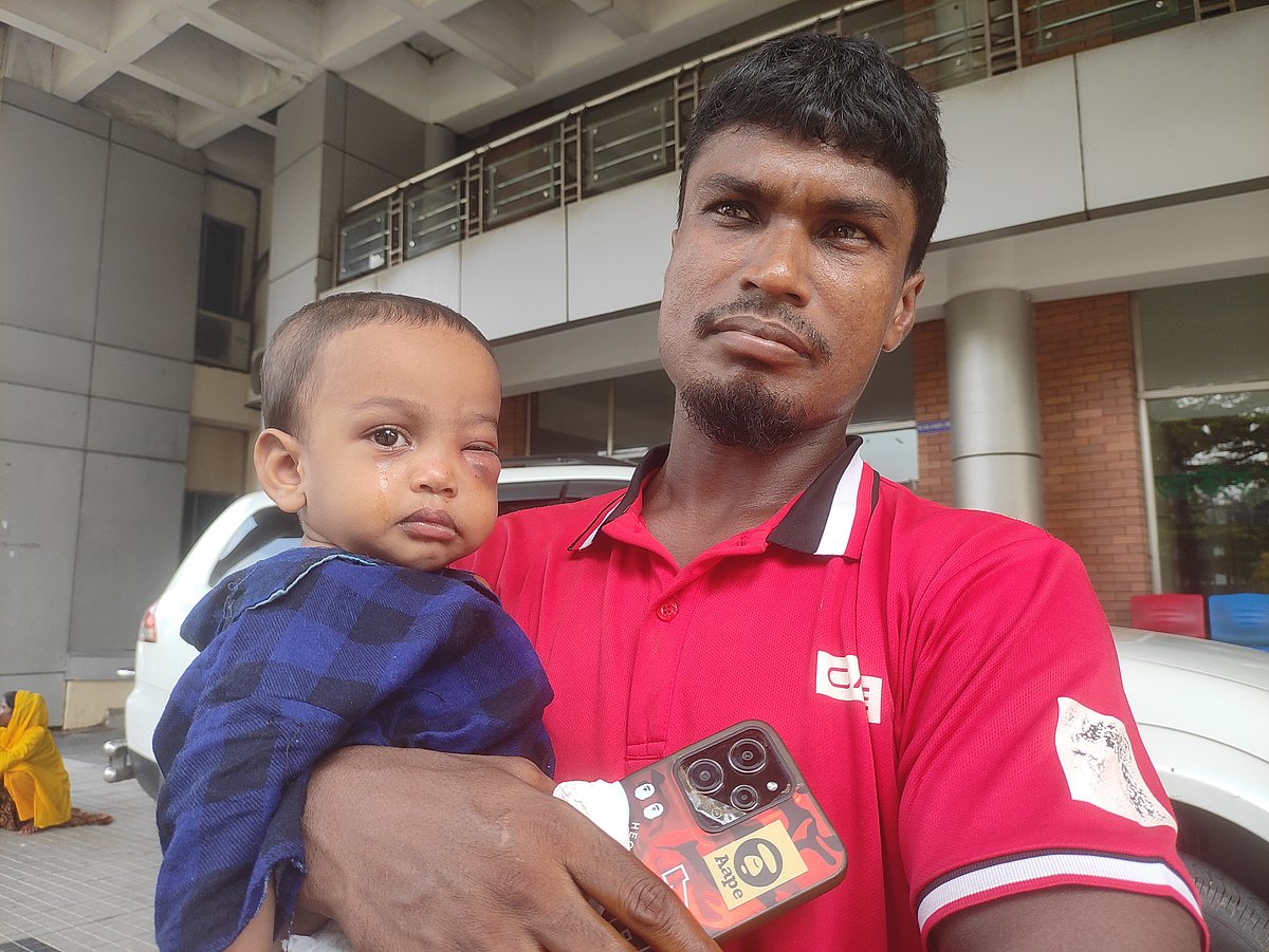 ছেলেকে কোলে নিয়ে চিকিৎসার আশায় ঢাকার আগারগাঁওয়ে জাতীয় চক্ষুবিজ্ঞান ইনস্টিটিউট ও হাসপাতালে এসেছেন এই বাবা