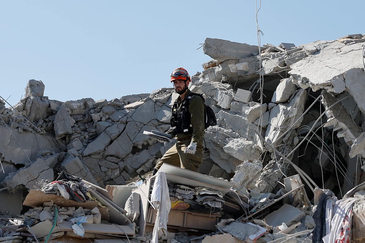 ইরানের ক্ষেপণাস্ত্রের আঘাতে ধ্বংসস্তূপে রূপ নিয়ে বহুতল ভবন। সেই ধ্বংসস্তূপের মধ্যে উদ্ধার তৎপরতায় ইসরায়েলি এক সেনাসদস্য। রিশন এলাকা, ইসরায়েল, ১৪ জুন, ২০২৫