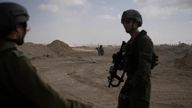 গাজা উপত্যকায় হামলায় ক্ষতিগ্রস্ত কয়েকটি ভবনের পাশ দিয়ে হেঁটে যাচ্ছেন কয়েকজন ইসরায়েলি সেনা