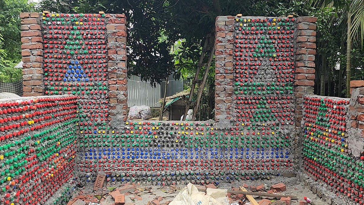 শরীয়তপুরের গোসাইরহাট উপজেলায় প্লাস্টিকের বোতল দিয়ে বাড়ির দেয়াল তৈরি করছেন ইমান ঢালী নামের এক ব্যক্তি