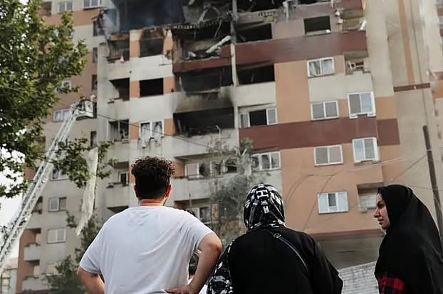 ইসরায়েলের হামলায় ক্ষতিগ্রস্ত একটি ভবনের সামনে ইরানের কয়েকজন নাগরিক