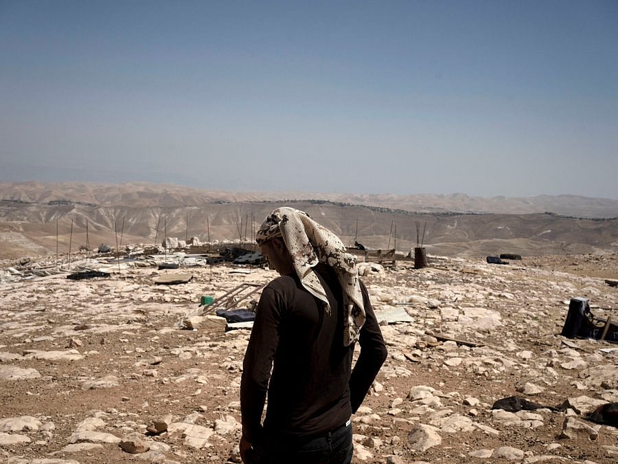 পশ্চিম তীরের বেদুইন গ্রামে ধ্বংসাবশেষের ওপর দাঁড়িয়ে আছেন এক ফিলিস্তিনি। গ্রামটির কাছে অবৈধ ইহুদি বসতি স্থাপনকারীরা একটি তল্লাশি ফাঁড়ি বসালে সেখান থেকে স্থানীয় বাসিন্দারা পালিয়ে যান