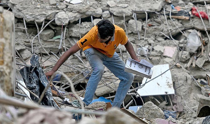 করাচির ধসে পড়া আবাসিক ভবনের ধ্বংসস্তূপের ভেতর নিজের জিনিসপত্র খুঁজছেন এক বাসিন্দা। ৫ জুলাই