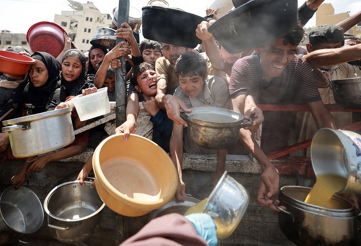 দাতব্য রান্নাঘরের সরবরাহ করা খাবার সংগ্রহ করতে ফিলিস্তিনিদের ভিড়। আজ সোমবার গাজা নগরীতে