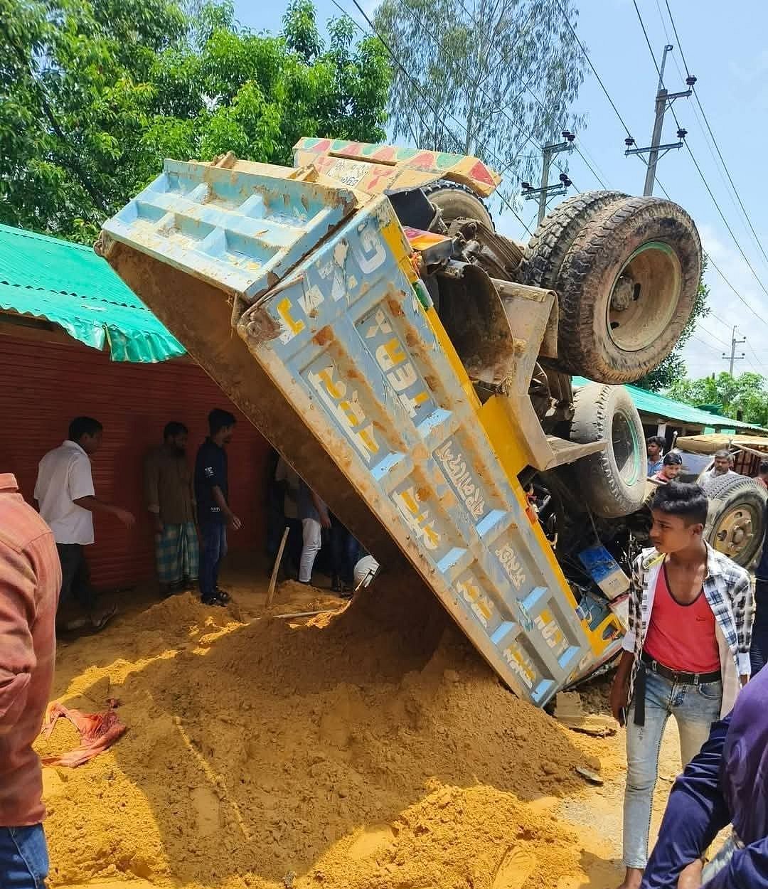 অটোরিকশাকে ধাক্কা দিয়ে উল্টে যাওয়া বালুবাহী মিনি ট্রাক। আজ দুপুরে কক্সবাজারের টেকনাফের হোয়াইক্যং ইউনিয়নের তুলাতুলি এলাকায়