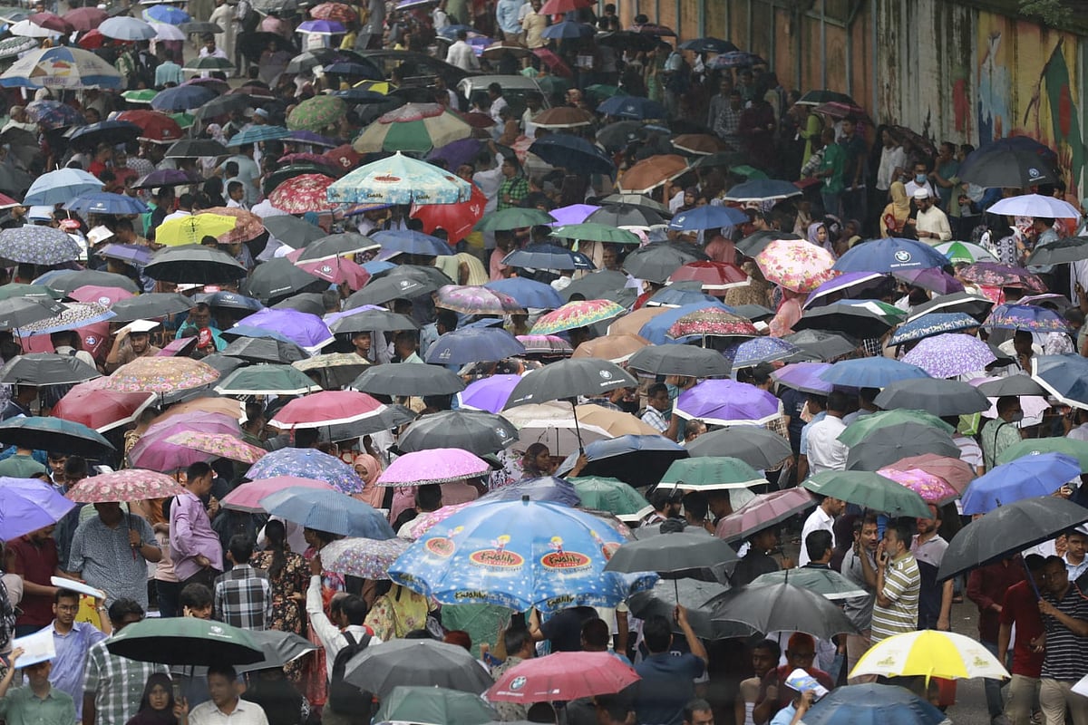 নটর ডেম কলেজে ভর্তি পরীক্ষায় অংশ নিতে আসা শিক্ষার্থীদের অভিভাবকেরা বৃষ্টির মধ্যে ছাতা মাথায় অপেক্ষা করছেন। নটর ডেম কলেজের সামনে,  ঢাকা, ৮ আগস্ট