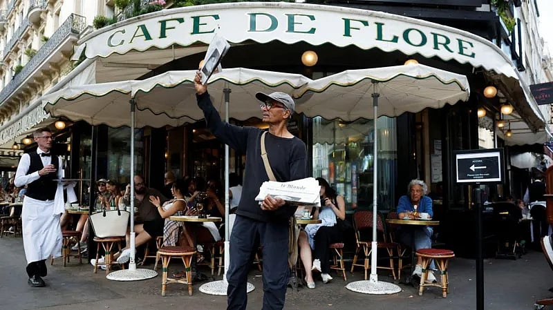 প্যারিসের একটি ক্যাফের সামনে পত্রিকা বিক্রি করছেন আলী আকবর