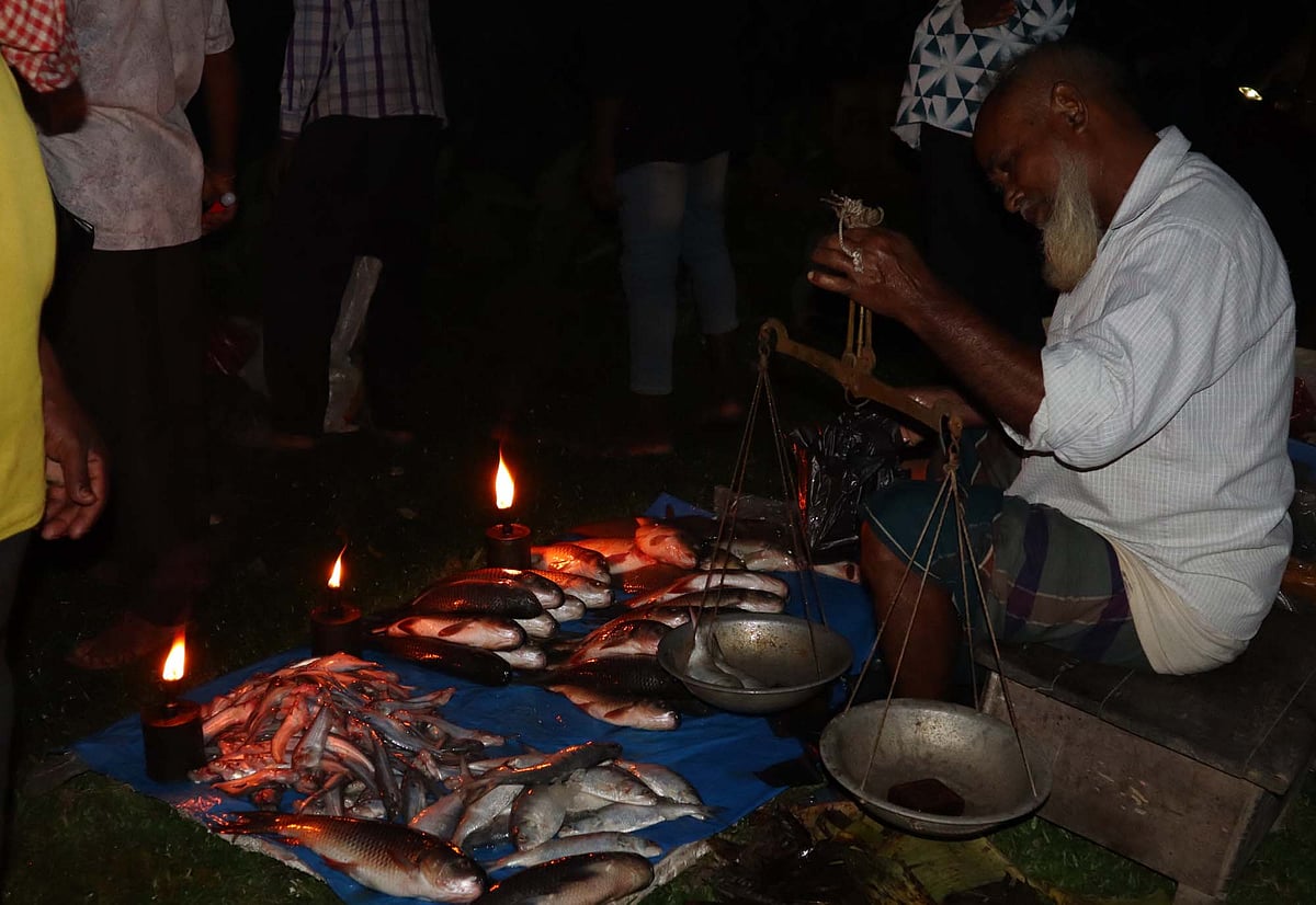কুপিবাতি জ্বালিয়ে বিক্রি করা হচ্ছে মাছসহ বিভিন্ন ধরনের পণ্য। গত বৃহস্পতিবার সন্ধ্যায় মৌলভীবাজারের কমলগঞ্জের মিরতিংগা হাটে