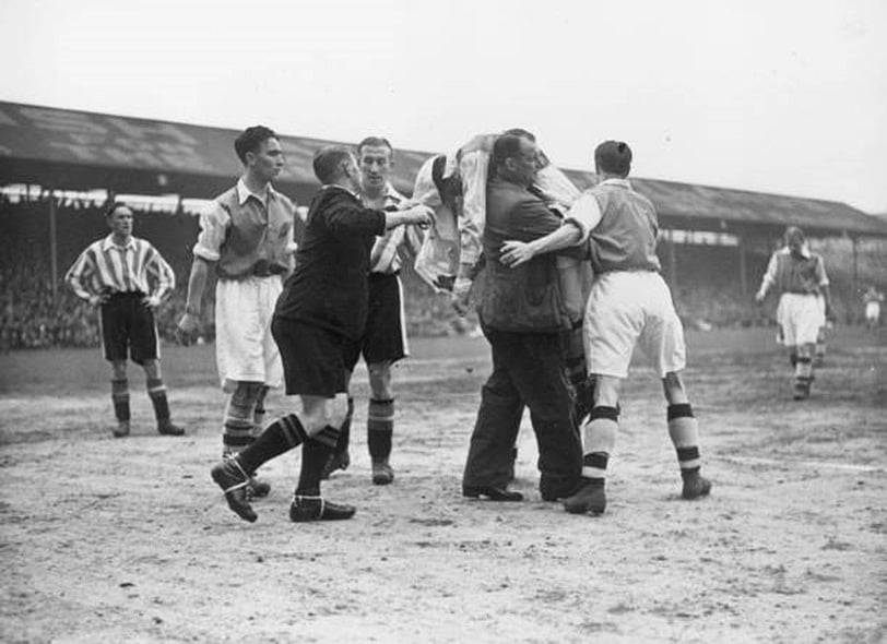 জ্ঞান হারানোর পর টেড ড্রেককে কাঁধে তুলে মাঠের বাইরে নিয়ে যান আর্সেনালের ট্রেনার টম হুইটেকার