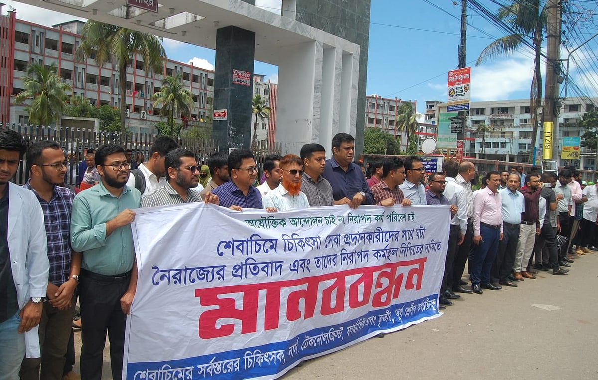 শের-ই-বাংলা মেডিকেল কলেজ হাসপাতালের চিকিৎসক-কর্মচারীরা হামলাকারীদের গ্রেপ্তার ও নিরাপদ কর্মপরিবেশের দাবিতে মানববন্ধন করেন। আজ সোমবার দুপুরে হাসপাতালের মূল ফটকের সামনে