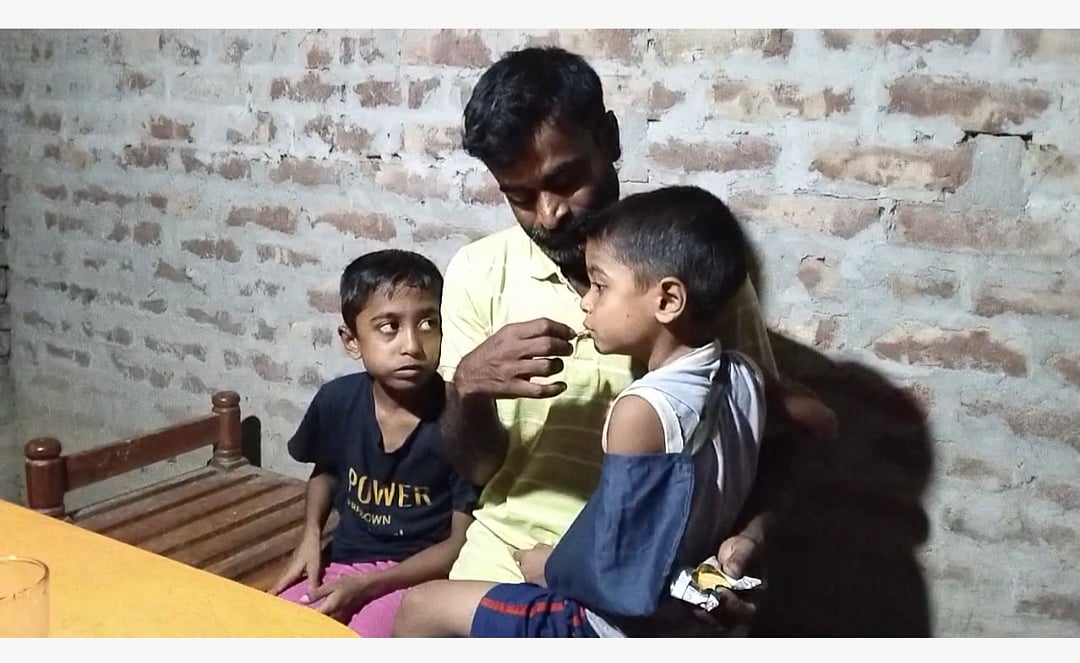 দুই সন্তানকে কোলে এবং পাশে নিয়ে বসে আছেন বাবা আবদুল হান্নান। আজ সোমবার