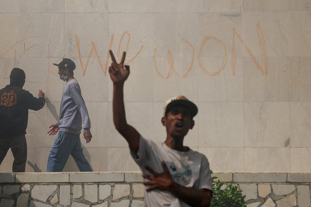 নেপালের পার্লামেন্ট ভবনের দেয়ালে লিখছেন এক ব্যক্তি। এ সময় বিজয় চিহ্ন দেখাচ্ছেন এক বিক্ষোভকারী। কাঠমান্ডু, ৯ সেপ্টেম্বর