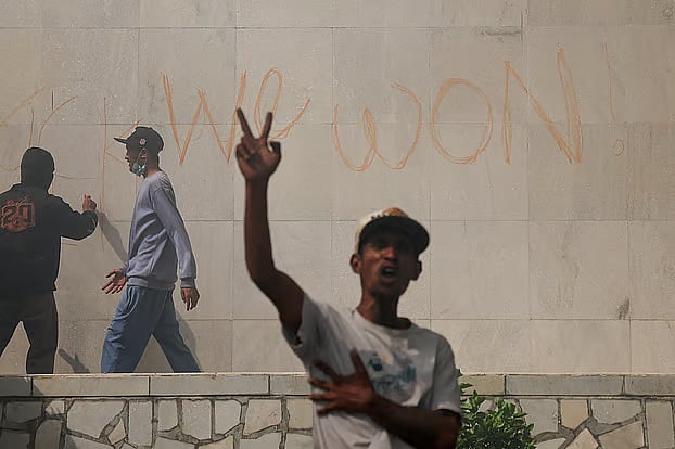 নেপালের পার্লামেন্ট ভবনের দেয়ালে লিখছেন এক ব্যক্তি। এ সময় বিজয়চিহ্ন দেখাচ্ছেন এক বিক্ষোভকারী। কাঠমান্ডু, ৯ সেপ্টেম্বর