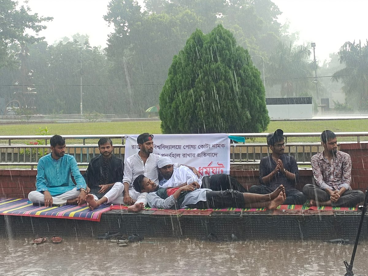 রাজশাহী বিশ্ববিদ্যালয়ে পোষ্য কোটা ফেরানোর প্রতিবাদে ঝুম বৃষ্টির মধ্যে শিক্ষার্থীদের আমরণ অনশন। আজ শনিবার বেলা ১১টা ২০ মিনিটের দিকে বিশ্ববিদ্যালয়ের প্রশাসন ভবনের সামনে।