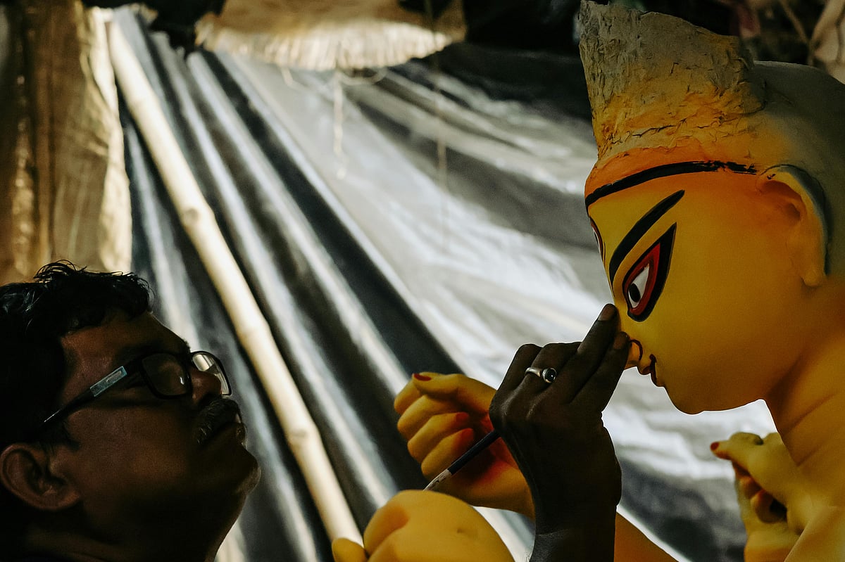 দুর্গার প্রতিমায় রঙ করছেন এক শিল্পী