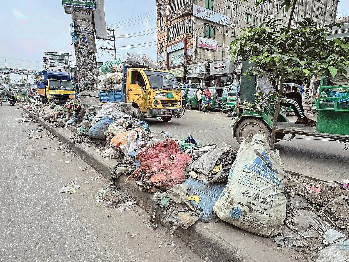ব্যস্ত রাস্তার সড়ক বিভাজকে ফেলে রাখা হয়েছে ময়লা-আবর্জনার বস্তা। মঙ্গলবার ঢাকার কেরানীগঞ্জের কদমতলী এলাকায়