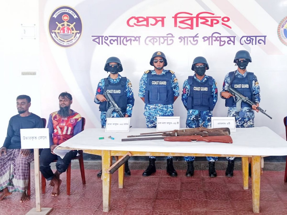সুন্দরবনে বনদস্যুদের হাত থেকে উদ্ধার করা আগ্নেয়াস্ত্র। পাশে উদ্ধার হওয়া জেলেদের দুজন। আজ শুক্রবার সকালে কোস্টগার্ড পশ্চিম জোনের কার্যালয়ে