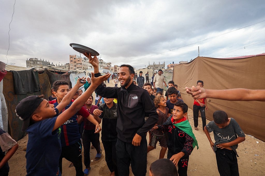 মিষ্টি বিতরণ করে ফিলিস্তিনিদের যুদ্ধবিরতির ঘোষণা উদ্‌যাপন। মধ্য গাজার নুসেইরাত এলাকায়, ৯ অক্টোবর ২০২৫