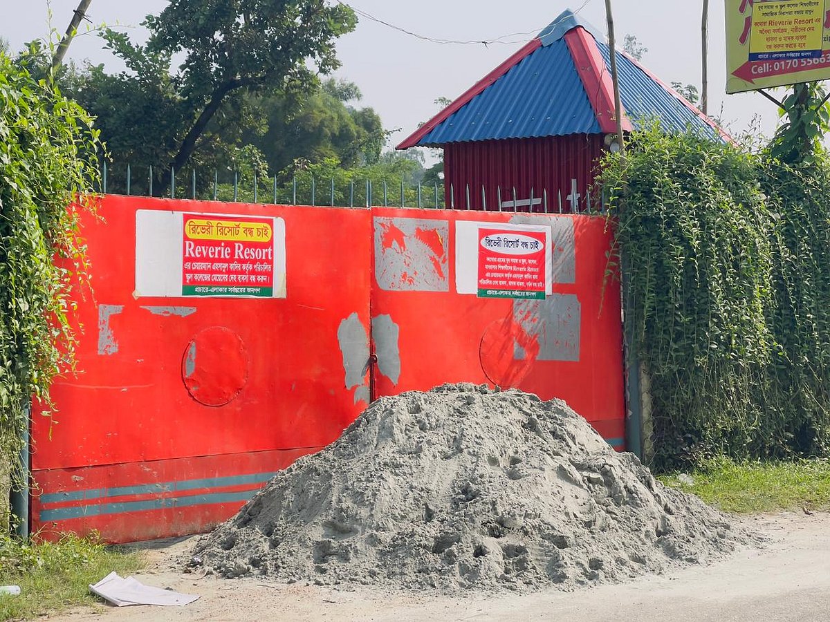 গাজীপুর মহানগরীর টেক কাথোরা এলাকায় রিভেরী রিসোর্টের ফটকের সামনে বালু ফেলে প্রতিবন্ধকতা সৃষ্টি করা হয়েছে। সেখানে লিখে রাখা হয়েছে রিভেরী রিসোর্টে বন্ধ চাই। গত বৃহস্পতিবারের ছবি