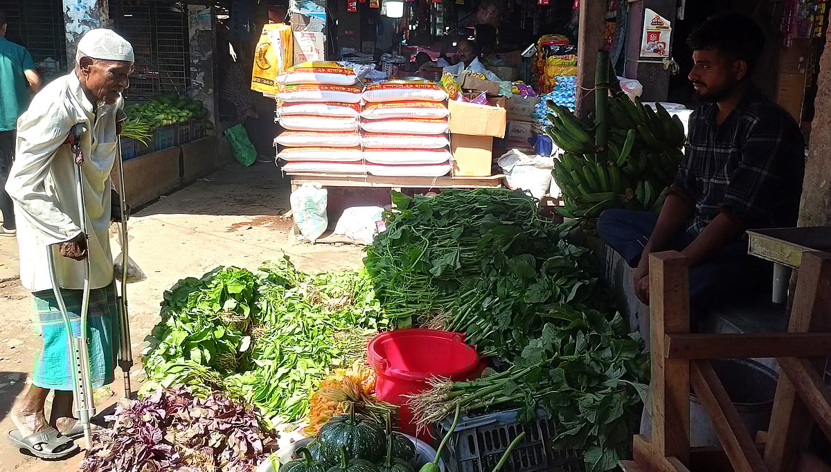 সকাল বাজারে শাক কিনছেন শারীরিক প্রতিবন্ধী আবদুল হামিদ। আজ মঙ্গলবার