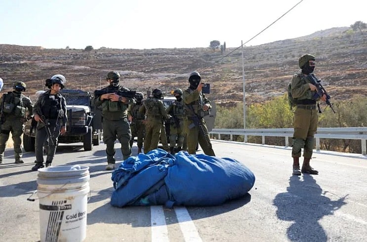 পশ্চিম তীরে একটি সড়কে অবস্থান নিয়েছেন কয়েকজন ইসরায়েলি সেনা। ২৩ অক্টোবর ২০২৫