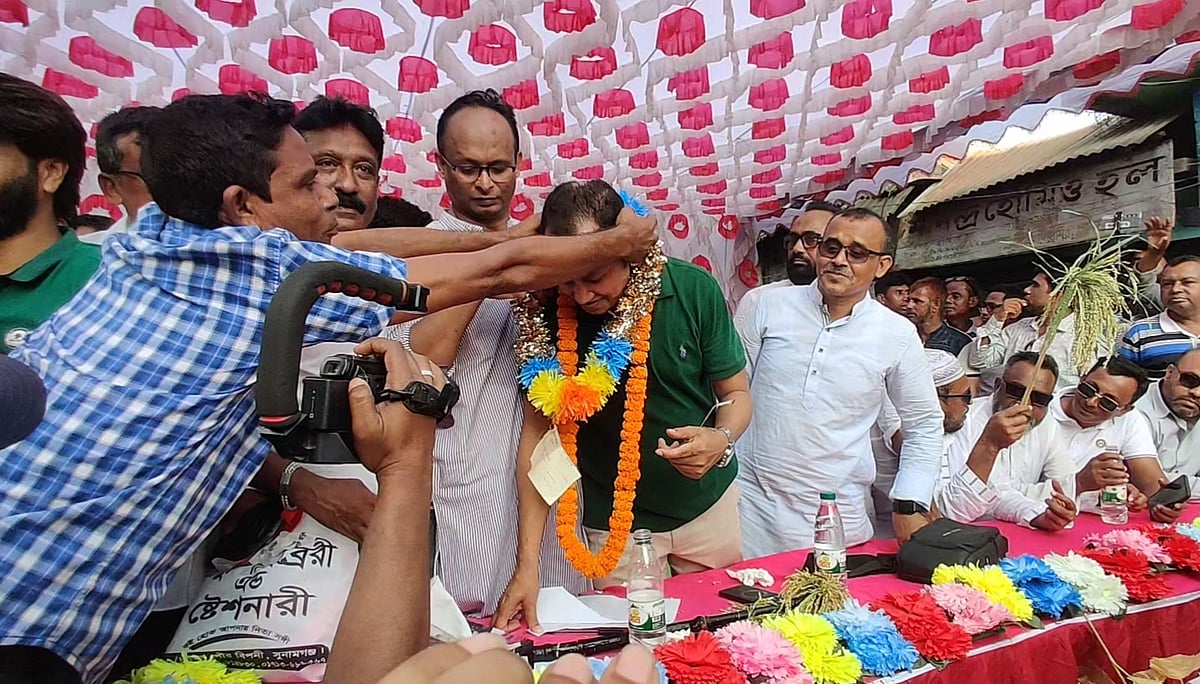 সুনামগঞ্জে সমাবেশ মঞ্চে ১০ লাখ টাকার চেক মালায় বেঁধে বিএনপি নেতা কামরুজ্জামানকে পরিয়ে দিচ্ছেন কর্মী নূর কাসেম (চেক শার্ট)। শনিবার বিকেলে জেলার জামালগঞ্জ উপজেলার সাচনাবাজারে