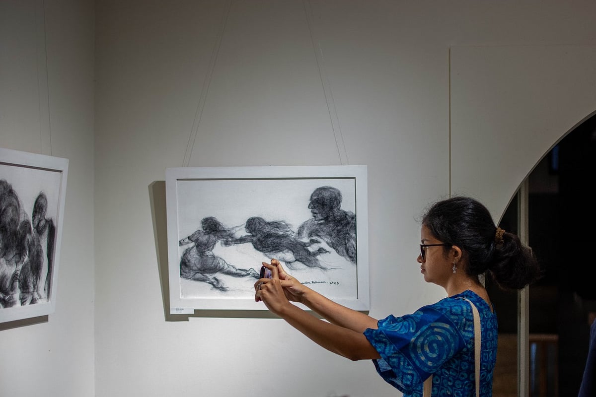 প্রদর্শনীতে রাখা ছবি ক্যামেরাবন্দী করছেন এক দর্শক