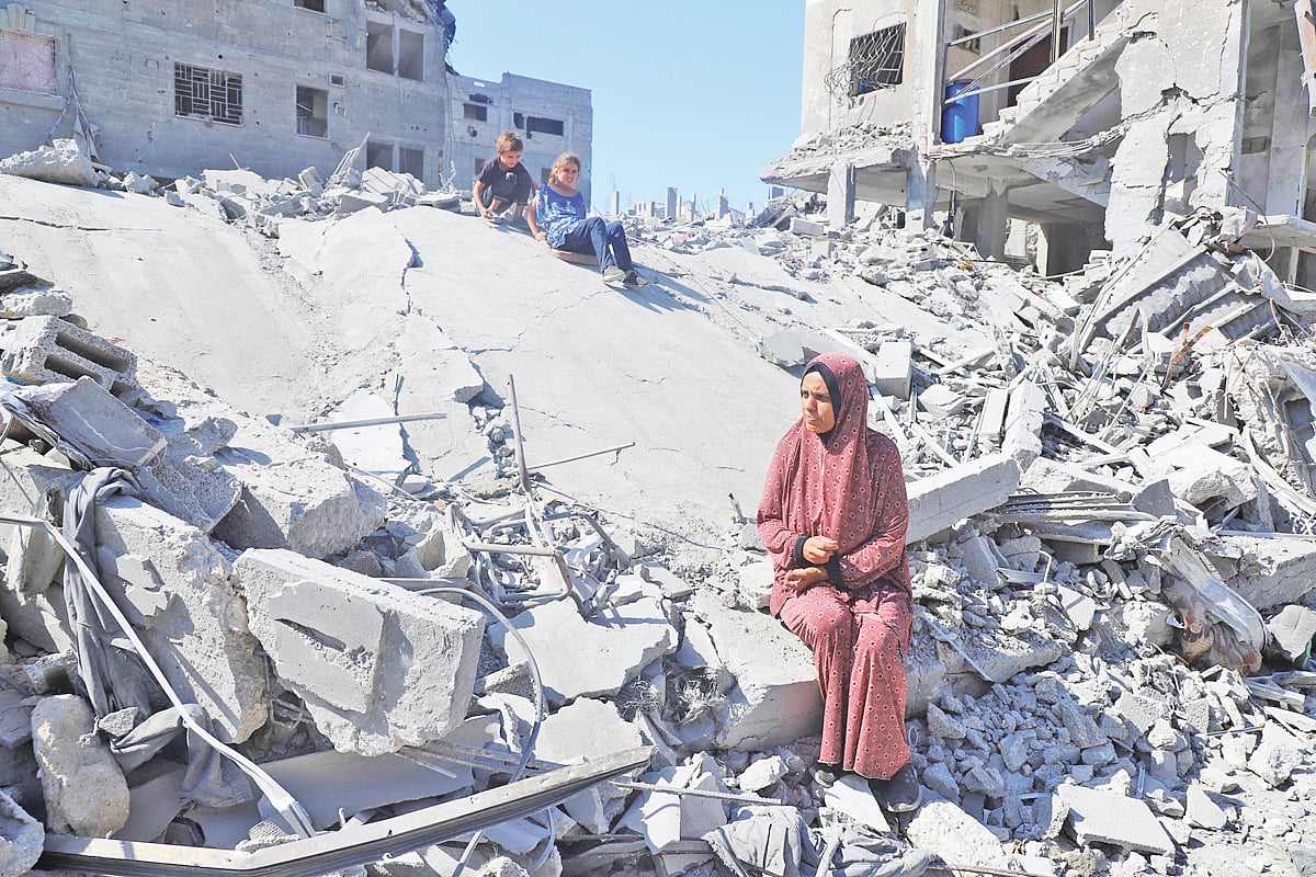 গাজা নগরীর আল-শাতি শরণার্থীশিবিরে ধ্বংসস্তূপে বসে আছেন বাস্তুচ্যুত ফিলিস্তিনি এক মা ও তাঁর সন্তানেরা