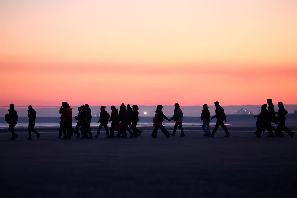 ইংলিশ চ্যানেল পাড়ি দিয়ে যুক্তরাজ্যে পৌঁছার জন্য উত্তর ফ্রান্সের উপকূল থেকে গ্যাস দিয়ে ফোলানো নৌকায় ওঠার জন্য যাচ্ছেন কিছু অভিবাসনপ্রত্যাশী। ফ্রান্সের ক্যালাইসের পেতি-ফোর্ট-ফিলিপে, ২৭ সেপ্টেম্বর ২০২৫