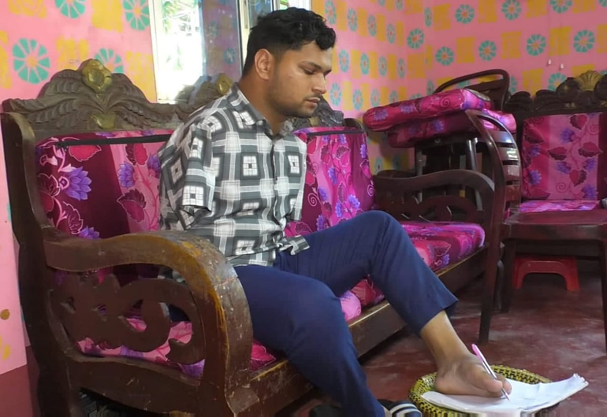 পা দিয়ে লিখছেন মো. আলী। সম্প্রতি তাঁর বাড়িতে