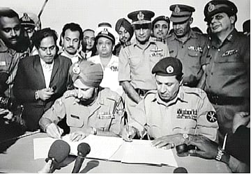 আত্মসমর্পণের দলিলে সই করছেন পাকিস্তানি বাহিনীর পূর্বাঞ্চলীয় কমান্ডের অধিনায়ক লেফটেন্যান্ট জেনারেল এ এ কে নিয়াজি। পাশে মিত্রবাহিনীর লেফটেন্যান্ট জেনারেল জগজিৎ সিং অরোরা, রেসকোর্স ময়দান, ১৬ ডিসেম্বর ১৯৭১