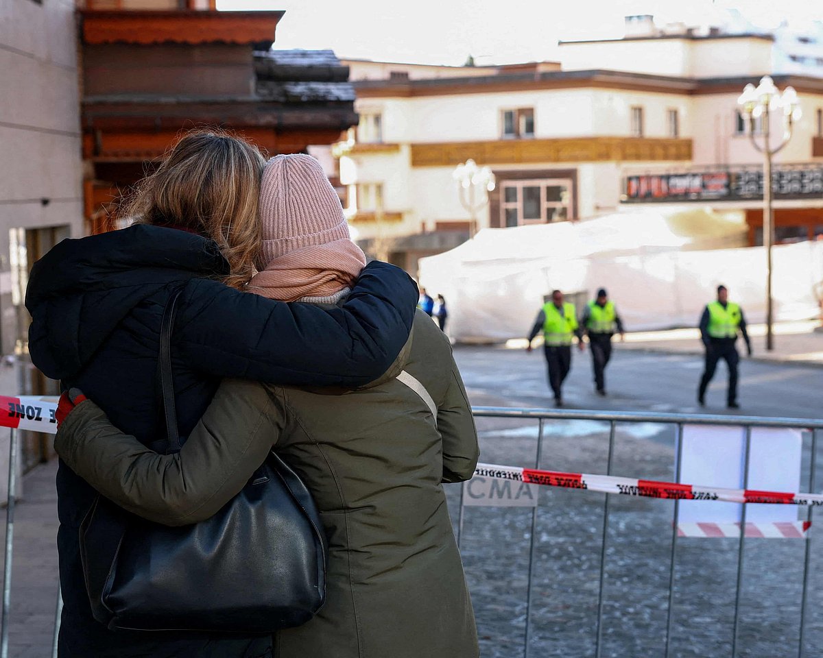আগুনে পুড়ে যাওয়া লে কনস্টেলেশন পানশালার পাশে একে অপরকে জড়িয়ে ধরে সান্ত্বনা দিচ্ছেন লোকজন