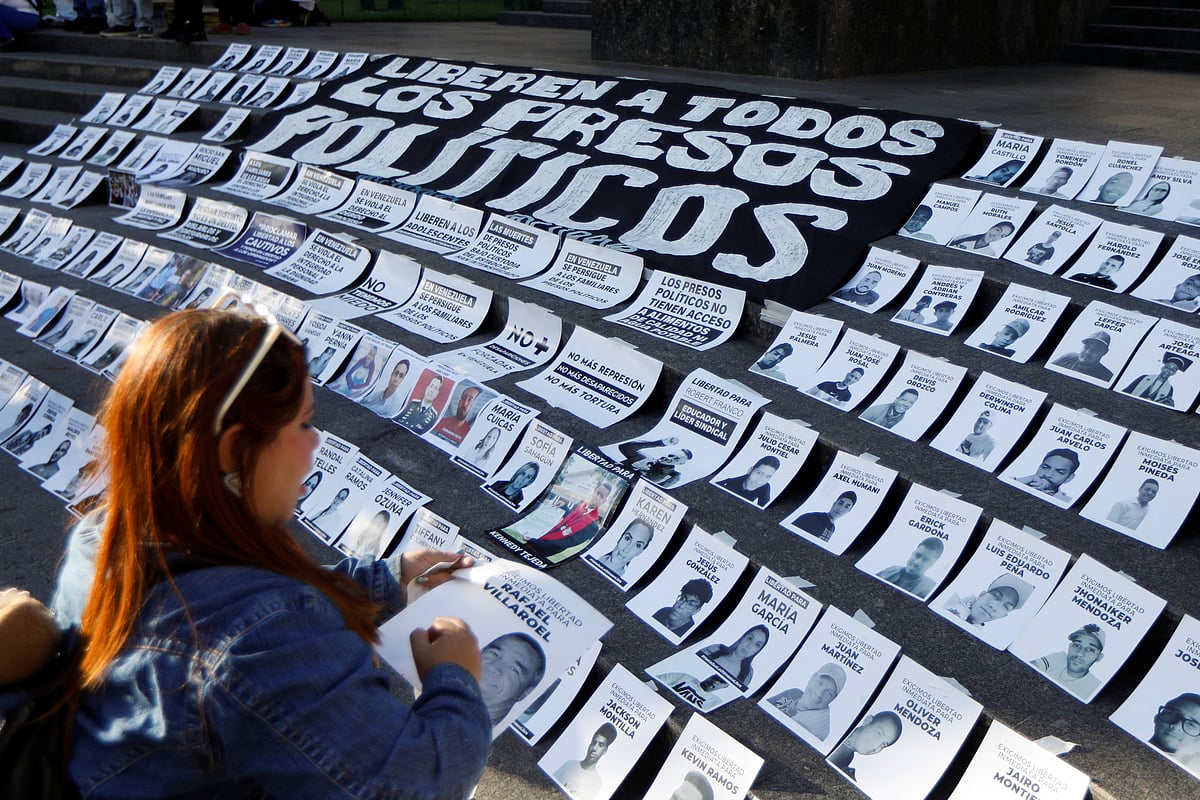 ‘ক্রিসমাস উইদাউট পলিটিক্যাল প্রিজনার্স’ নামে একটি বিক্ষোভে রাজনৈতিক বন্দীদের ছবি সাজিয়ে রাখছেন এই নারী। কারাকাস, ভেনেজুয়েলা, ১৪ ডিসেম্বর ২০২৫