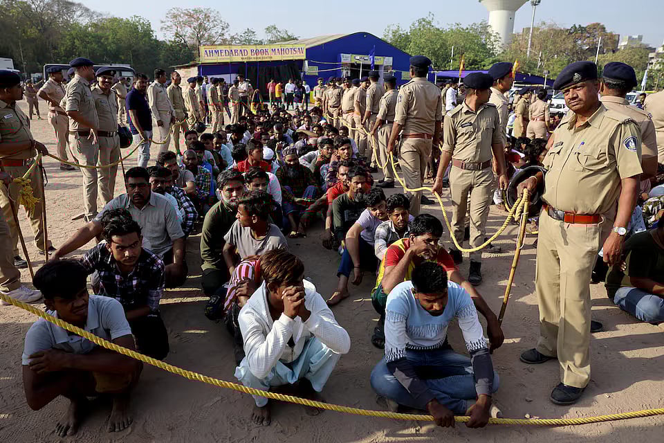 কাগজপত্র ছাড়া ভারতে আসা বাংলাদেশি সন্দেহে আটকদের পাশে দাঁড়িয়ে রয়েছেন পুলিশ কর্মকর্তারা। ভারতের আহমেদাবাদে, ২৬ এপ্রিল ২০২৫