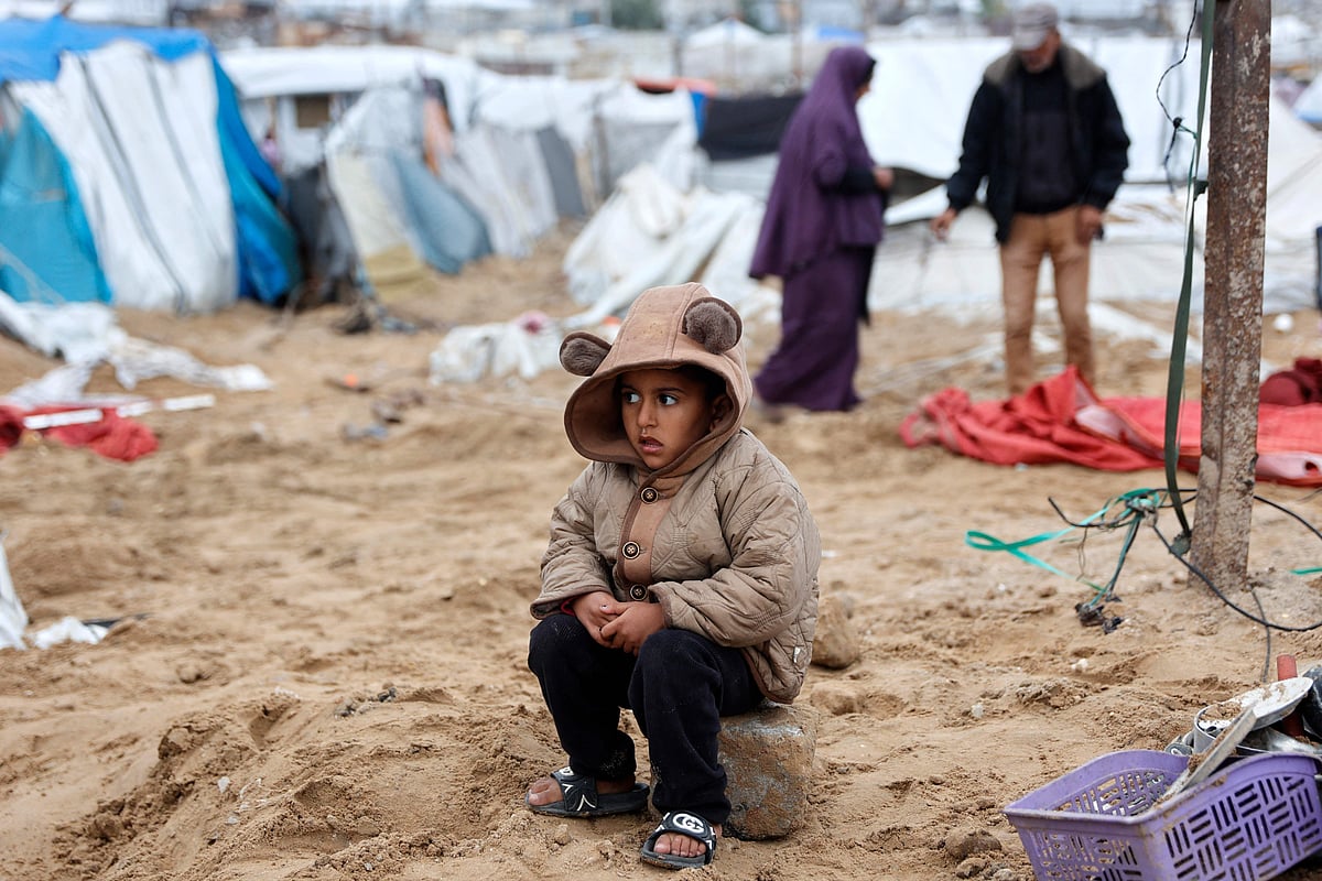ইসরায়েলি হামলায় ছিন্নভিন্ন হয়ে গেছে তাঁবু। সেটি আবার গোছানোর চেষ্টায় পরিবারের সদস্যরা। উৎকণ্ঠা নিয়ে সেখানে বসে আছে এক ফিলিস্তিনি শিশু। ৯ জানুয়ারি ২০২৬; গাজা নগরী, ফিলিস্তিন
