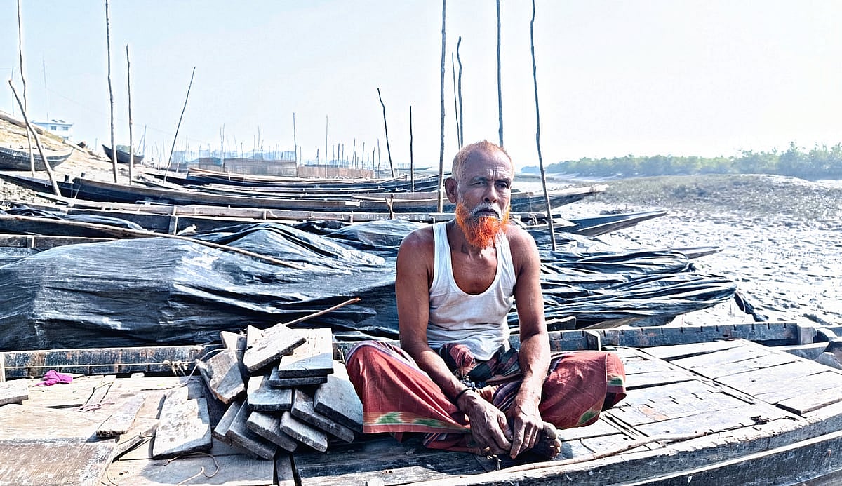 সুন্দরবন–সংলগ্ন আড়পাঙ্গাসিয়া নদীর চরে রাখা একটি নৌকায় বসে কওসার গাইন
