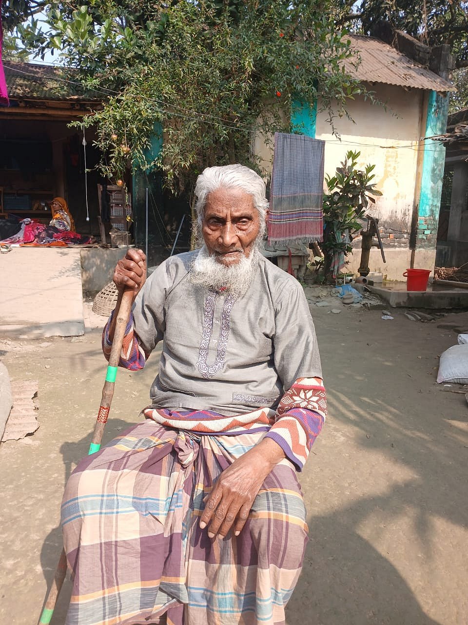 উঠানে বসে রোদ পোহাচ্ছেন শতবর্ষী শামসুল হক