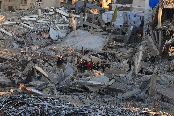 গাজা সিটিতে যুদ্ধের সময় ধ্বংস হওয়া আবাসিক ভবনের স্তূপের পাশ দিয়ে যাচ্ছেন ফিলিস্তিনিরা। ১৬ জানুয়ারি, ২০২৬