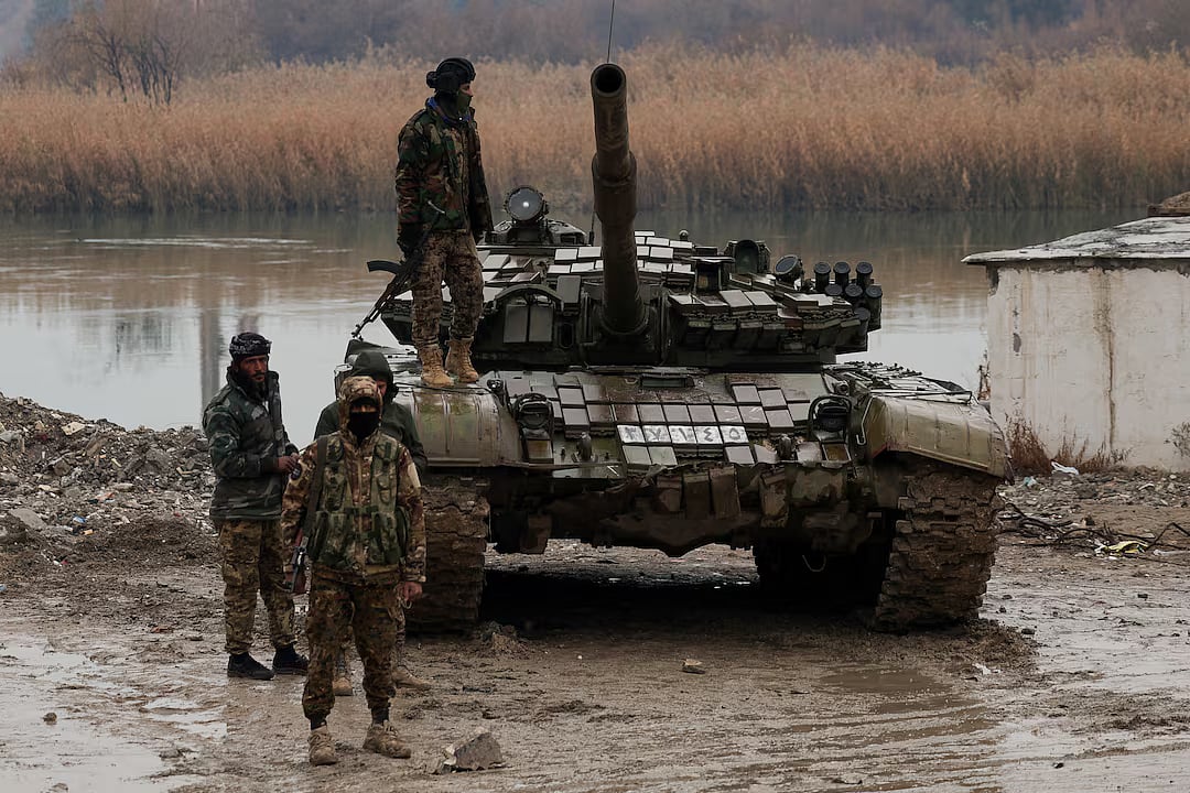 ফোরাত নদীতে সংযুক্তকারী একটি স্থানে দাঁড়িয়ে আছেন সিরিয়ার সরকারি বাহিনীর কিছু সদস্য। দেইর আল-জোর প্রদেশে, ১৮ জানুয়ারি ২০২৬