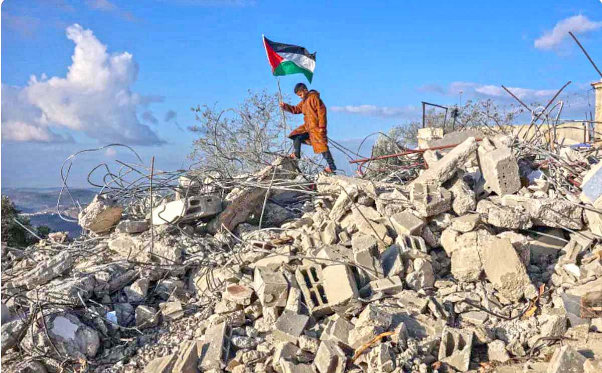পশ্চিম তীরের ফিলিস্তিনি গ্রাম বাজরিয়ায় ইসরায়েলি সেনাবাহিনীর ধ্বংস করে দেওয়া একটি বাড়ির ধ্বংসস্তূপের ওপর পতাকা হাতে এক কিশোর