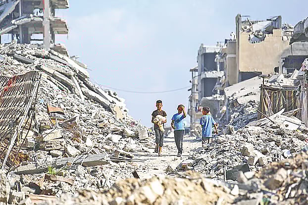 গাজায় ধ্বংসস্তূপের ভেতর দিয়ে হেঁটে চলেছে ফিলিস্তিনি কিশোরেরা। গাজা নগরীর আল-শাতি শরণার্থীশিবিরের পাশে। ৮ নভেম্বর ২০২৫