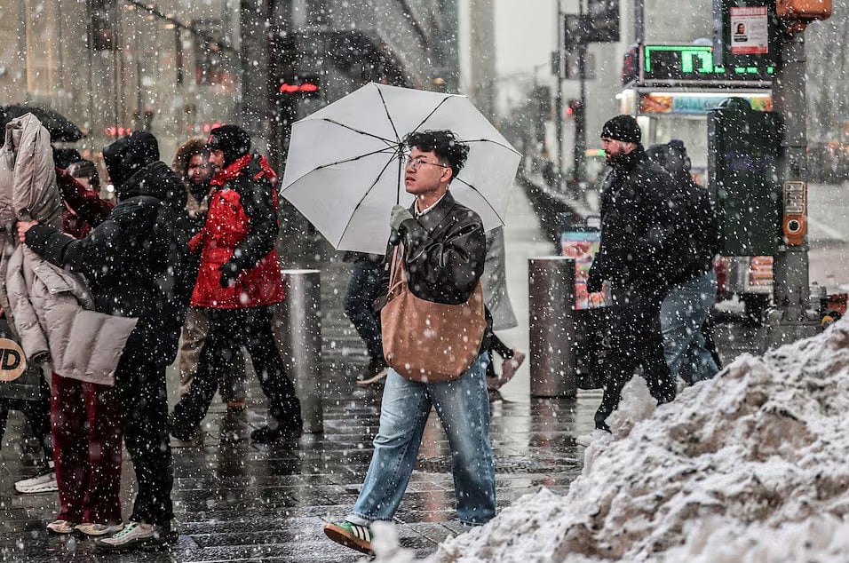 নিউইয়র্ক সিটিতে শীতকালীন তুষারঝড়ের সময় তুষারপাতের মধ্যে রাস্তায় হাঁটছেন পথচারীরা