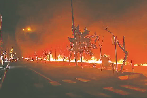 ইরানে জ্বালানি ডিপোতে হামলার পর নালায় ছড়িয়ে পড়া তেলে আগুন জ্বলছে। শনিবার দিবাগত রাতে রাজধানী তেহরানে