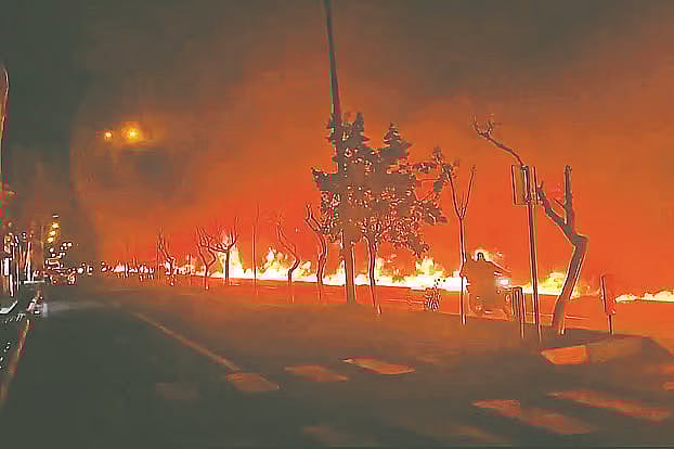 ইরানের রাজধানী তেহরানে শনিবার দিবাগত রাতে জ্বালানি ডিপোতে হামলার পর নালায় ছড়িয়ে পড়া তেলে জ্বলছে আগুন