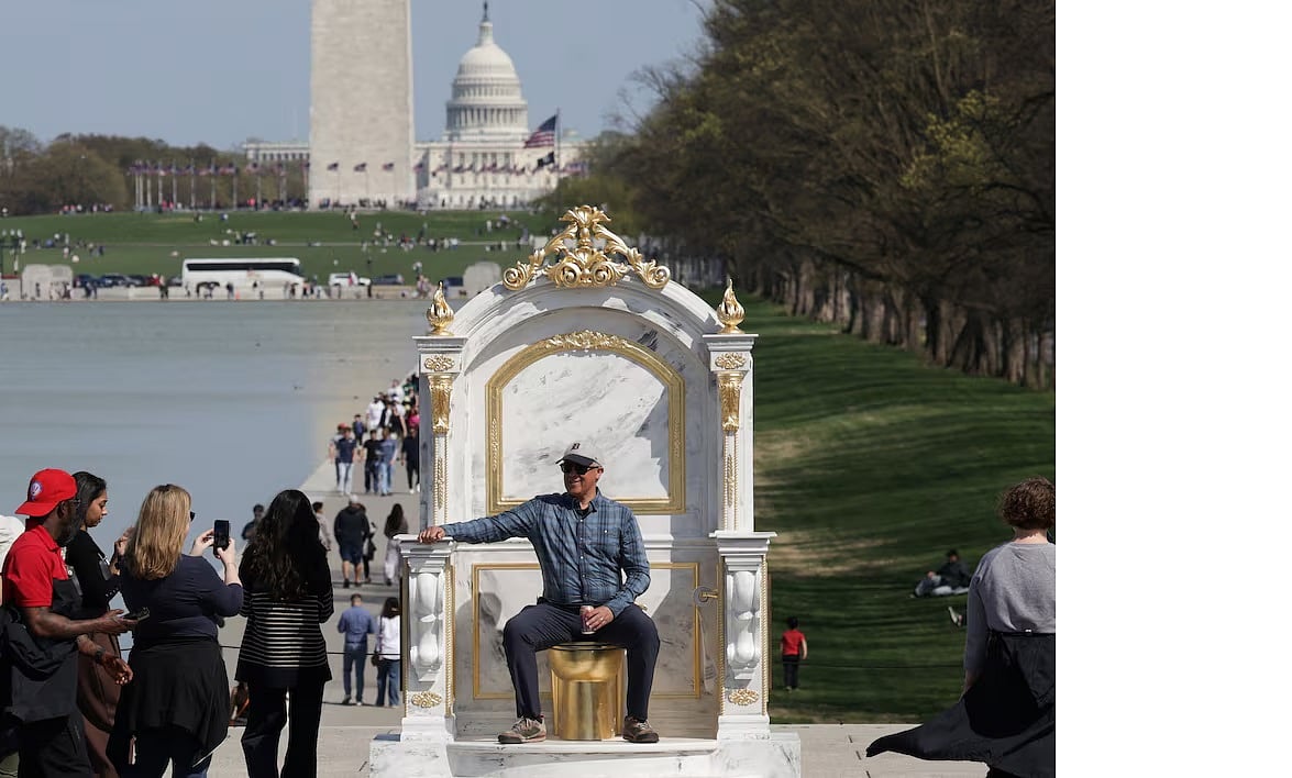 ওয়াশিংটনের ন্যাশনাল মলে ‘রাজার উপযুক্ত সিংহাসন’ শিরোনামে তৈরি প্রতীকী সিংহাসন তৈরি করেছেন। এতে অনেকে বসে ছবি তুলছেন। ৩০ মার্চ ২০২৬, ওয়াশিংটন ডিসি।
