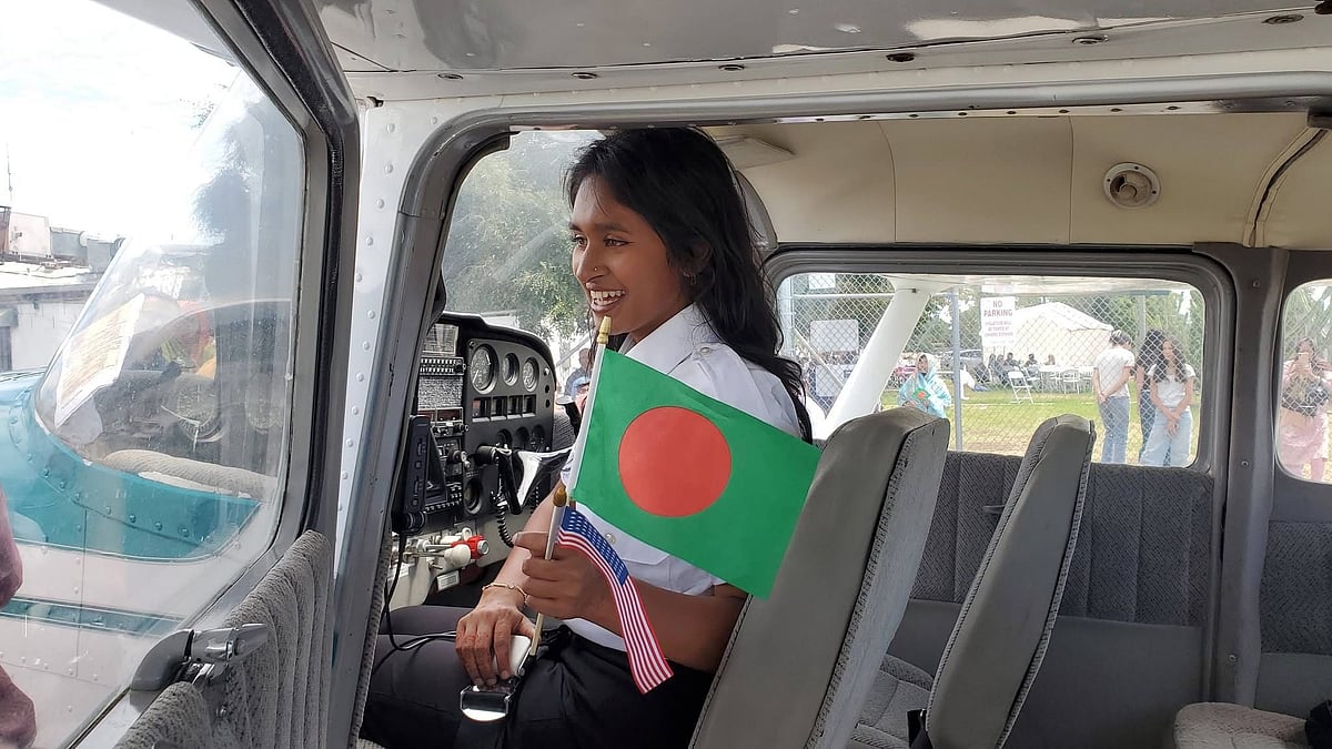 বিমানের ককপিটে বসে হাতে বাংলাদেশ ও যুক্তরাষ্ট্রের পতাকা নিয়ে উচ্ছ্বাস প্রকাশ করছে এভা ছোয়া